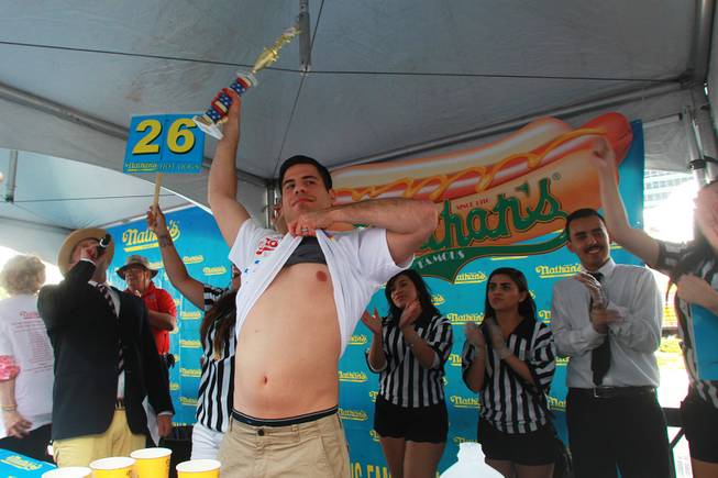 Pablo Martinez displays his stomach and trophy after winning the qualifying round for Nathan's Famous Fourth of July Hot Dog Eating Contest Saturday, April 26, 2014 at New York New York.