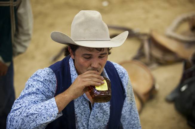 Fresno saddle bronc rider John Giacone takes a sip of Crown Royal for courage during the West Coast Regional Finals Rodeo at South Point Arena  on Friday, April 25, 2014.