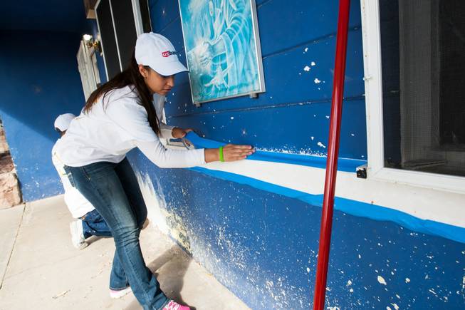 Volunteer Clarissa Tovar and Sam Berninger, left, tape windows in preparation for painting the home of former magician Gary Darwin, who lost his leg to diabetes, as part of the Rebuilding Together Southern Nevada's annual neighborhood rebuilding event in Las Vegas Saturday, April 26, 2014.