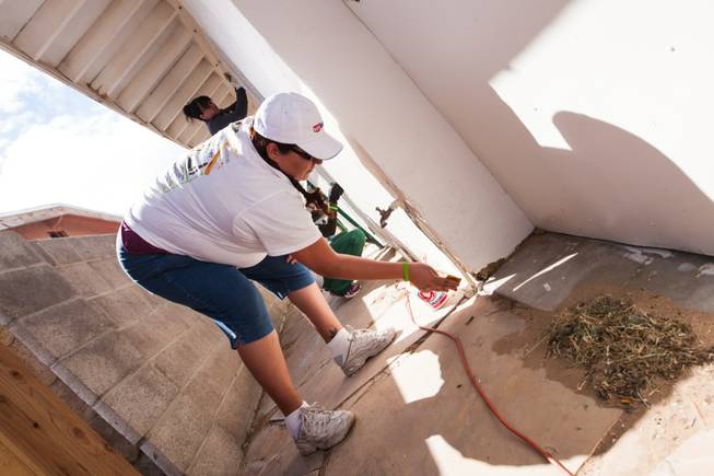 Volunteer Esperanza Meisner sands a water spigot on the side of the home of former magician Gary Darwin, who lost his leg to diabetes, as part of the Rebuilding Together Southern Nevada's annual neighborhood rebuilding event in Las Vegas Saturday, April 26, 2014.