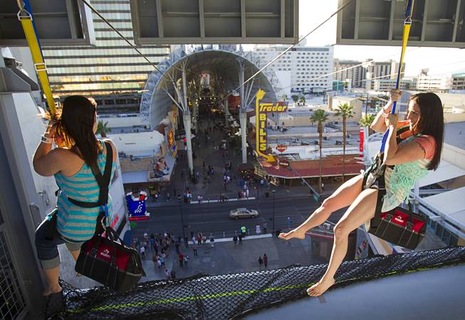 Tourists hang from a 77-foot-high launching area at the new 850-feet-long SlotZilla Zipline at the Fremont Street Experience in downtown Las Vegas, Wednesday, April 30, 2014. A higher and longer 1700-feet-long Zoomline, which will propel flyers in a horizontal "superman" position at speeds up to 35 mph, is expected to open in June. The zip-line, part of the $12 SlotZilla million project, opened Sunday.