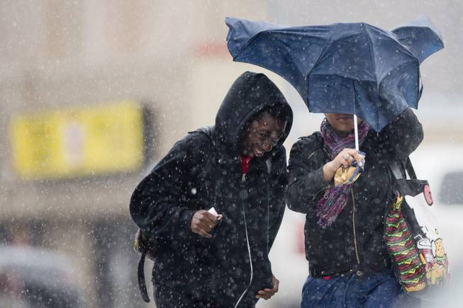 Pedestrians walk with little protection from their collapsed umbrella during a rainstorm, Wednesday, April 30, 2014, in Philadelphia. The area can expect widespread showers with possible thunderstorms with a flood watch in effect through Thursday morning. 