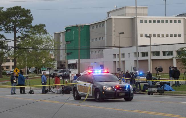 Police keep the media back outside the Escambia County Central Booking and Detention Center on Thursday, May 1, 2014, in Pensacola, Fla. The jail already had two feet of water in the basement from the record-setting rains when an apparent gas explosion leveled the inside of the building, killing two inmates and injuring more than 180 other people, officials said.