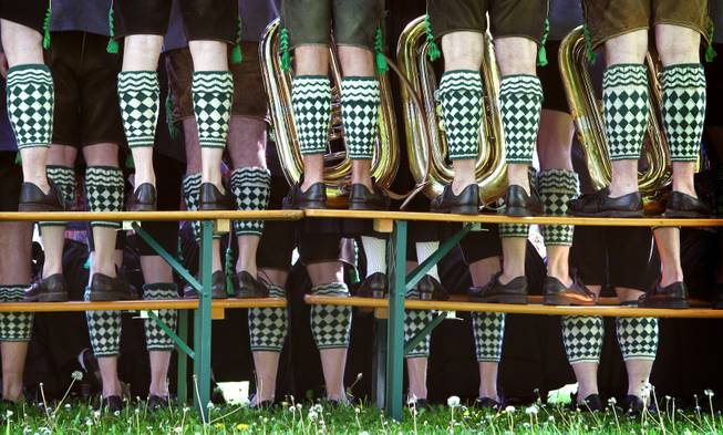 Musicians of the band Garmisch wearing traditional Bavarian costumes stand on beer benches and tables to take a group photo during May Day celebrations in the spa park of Garmisch-Partenkirchen, southern Germany, Thursday, May 1, 2014.