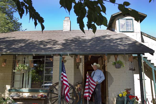 Rancher Cliven Bundy stands at his ranch house Sunday, May 4, 2014, near Bunkerville. The flag he is holding was flown on a hill April 12 when Bundy family members and supporters retrieved Bundy cattle from the Bureau of Land Management.