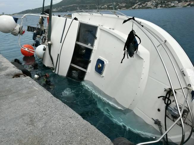 In this photo released by the Hellenic Coast Guard, divers search a yacht used to transport immigrants illegally that overturned in a fatal accident at the port of Vathy on the Greek island of Samos, on Monday, May 5, 2014.
