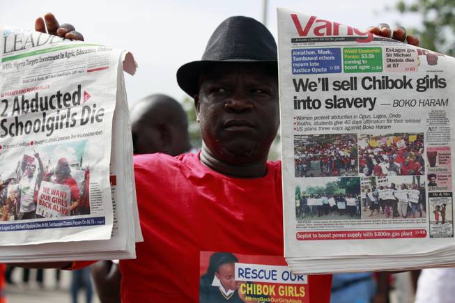 A man display copies of local newspapers during a demonstration calling on the government to rescue kidnapped school girls from Chibok government secondary school, outside the defense  headquarters, in Abuja, Nigeria, Tuesday, May 6, 2014.  