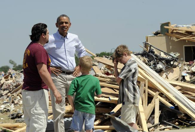 President Barack Obama tours tornado-damaged areas of Vilonia, Ark., Wednesday, May 7, 2014, and talks with Daniel Smith and his sons Garrison Dority and Gabriel Dority, right.