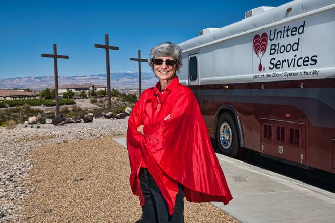 Dressed in a red cape emulating a droplet of blood, GriefShare facilitator Carol Von Eschen stands in front of the United Blood Services' mobile van waiting to greet church members during their blood drive at New Song Church in Henderson Sunday, April 6, 2014.