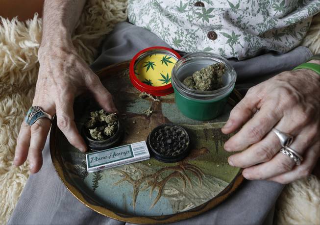 In this April 30, 2014 photo, Bill Britt, 54, who suffers from epileptic seizures and leg pain from a childhood case of polio, prepares a medical marijuana joint at his home in Long Beach, Calif. 
