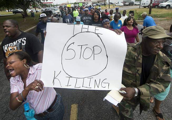 K.K. Davis, left, and Tommy Jones of Hearne carry a sign with other protesters outside the Hearne, Texas police department Thursday, May 8, 2014 following the Tuesday shooting of 93-year-old woman.