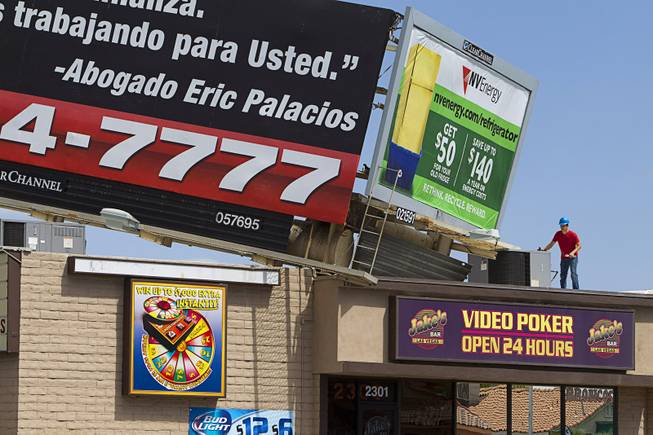 A worker looks over a billboard on the top of Jake's Bar on Eastern Avenue by Sahara Avenue Sunday, May 11, 2014. High winds apparently caused the the billboard to fall on the bar late Saturday night.