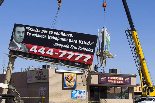Workers remove a section of a billboard from the top of Jake's Bar on Eastern Avenue by Sahara Avenue Sunday, May 11, 2014. High winds apparently caused the the billboard to fall on the bar late Saturday night.