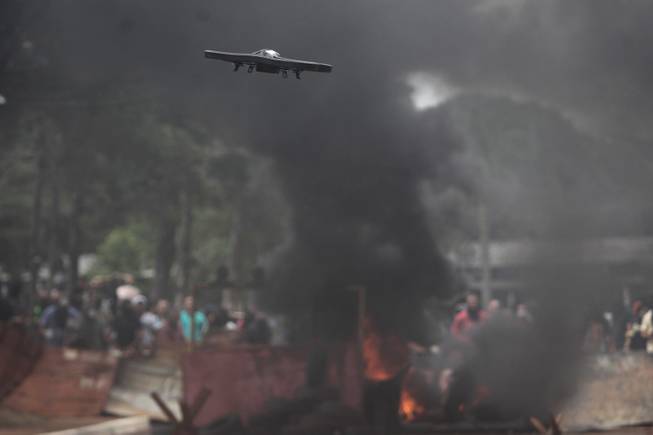 In this Sunday, March 30, 2014 photo, a drone flies during a mock protest as police train for World Cup security in Brasilia, Brazil. Brazil will host the soccer tournament starting in June. 