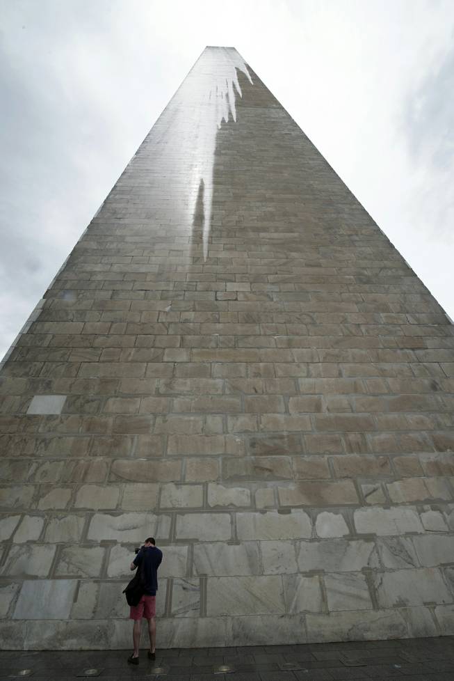 In this Saturday, May 10, 2014 photo, a journalist photographs the Washington Monument during a press preview prior to the re-opening of the monument, in Washington. With more than 150 cracks patched and repaired in its white marble, the Washington Monument is set to reopen for the first time since a 2011 earthquake caused widespread damage. 