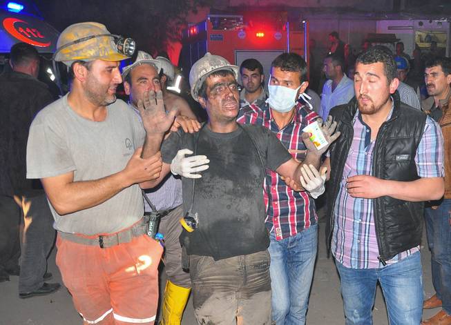 Miners escort a rescued friend after an explosion and fire at a coal mine in Soma, in western Turkey, Tuesday, May 13, 2014.  