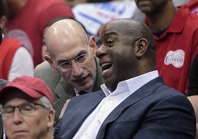 NBA Commissioner Adam Silver talks with Magic Johnson as they watch the Los Angeles Clippers play the Oklahoma City Thunder in the first half of Game 4 of the Western Conference semifinal NBA playoff series Sunday, May 11, 2014, in Los Angeles.