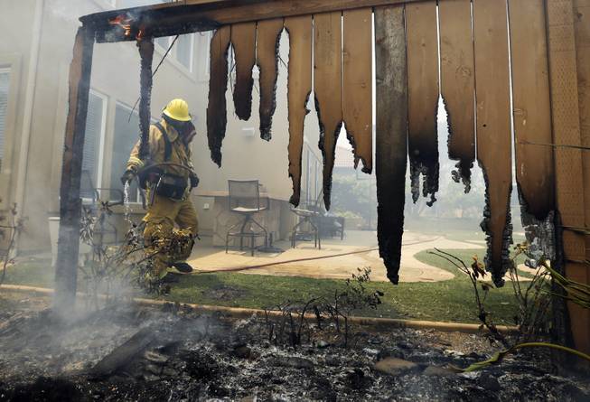 A Firefighter puts water on a house fence during a wildfire Wednesday, May 14, 2014, in Carlsbad, Calif. More wildfires broke out Wednesday in San Diego County  threatening homes in Carlsbad and forcing the evacuations of military housing and an elementary school at Camp Pendleton  as Southern California is in the grip of a heat wave. (AP Photo)