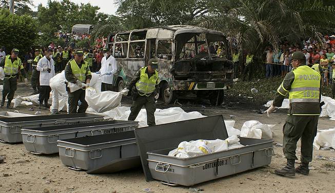 Police carry bags containing the remains of children who burned to death in the bus parked behind in Fundacion in northern Colombia, Sunday, May 18, 2014. 
