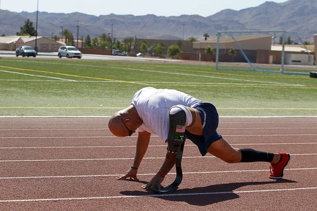 Mstr. Sgt. Christopher Aguilera stretches out at the outdoor track at Nellis Air Force Base Wednesday, May 21, 2014. Aguilera was selected as one of 40 Air Force members to participate in the 2014 London Invictus Games for wounded veterans. Aguilera was injured when his helicopter was shot down in Afghanistan in 2010.
