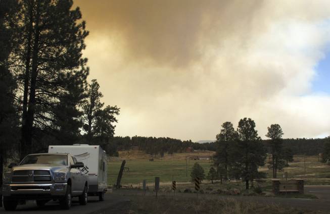 A vehicle heads out of Kachina Village in northern Arizona as a wildfire sends plumes of smoke into the air Wednesday, May 21, 2014. Hundreds of firefighters poured into the area to battle the wind-whipped blaze. 