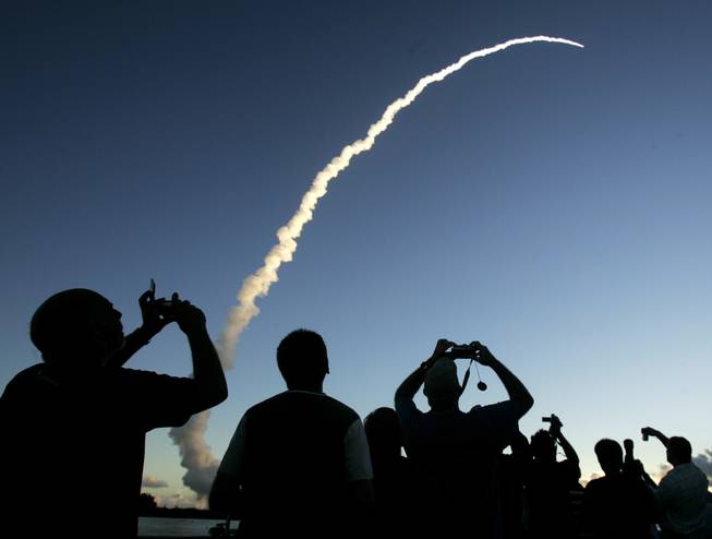 In this  Sept. 27, 2007 file photo, spectators at Jetty Park pier watch as a Delta II rocket lifts off from the Cape Canaveral Air Force Station in Cape Canaveral, Fla.
