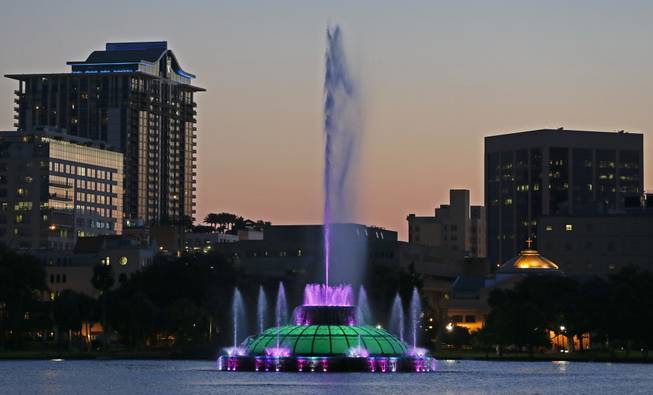 In this May 19, 2014, photo, water rises from a five-decade-old, green, multi-tiered fountain on Lake Eola that is the official icon of the city as the sun sets in Orlando, Fla. Every night, passersby are treated to a six-minute water show from the fountain featuring multicolored bursts of water timed to music.