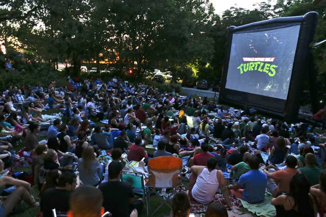 In this May 21, 2014 photo, people watch a free outdoor movie at the Enzian Theater in Maitland, Fla. The Enzian screens kitschy classics like Teenage Mutant Ninja Turtles and Videodrome on its front lawn, without charge, every other week.