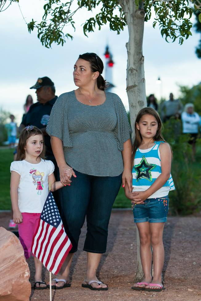 Kelli McCrimmon and her daughters, Joslynne, 4, and Jadynne, 8, listen with reverence as the names of fallen officers are read during the Southern Nevada Law Enforcement Memorial ceremony at Police Memorial Park in Las Vegas Thursday, May 22, 2014.