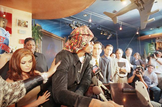 Dennis Rodman is comforted by his wife Carmen Electra, left, and an unidentified supporter as he breaks into tears amid skeptical questioning during a news conference in Beverly Hills, California on Monday, Feb. 22, 1999. 