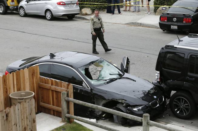 A Santa Barbara County deputy sheriff looks at the black BMW sedan driven by a drive-by shooter on Saturday, May 24, 2014, in Isla Vista, Calif. The shooter went on a rampage near a Santa Barbara university campus that left seven people dead, including the attacker, and others wounded, authorities said Saturday.