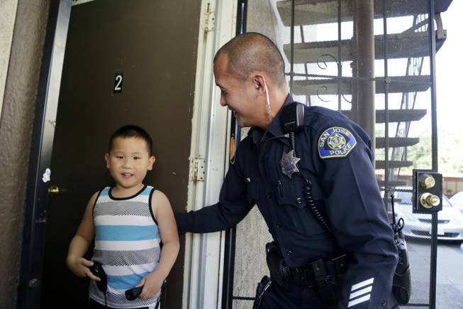 In this May 21, 2014 photo, San Jose police officer Huan Nguyen, right, visits with Steven Lam in San Jose, Calif. Nguyen came to the aid Lam and his family after the boy's father, Phuoc Lam, was killed during a road rage incident. Just two weeks since the murder, close to $100,000 in aid has poured in, from the local Vietnamese community and far beyond, including Houston, Boston, New York, even London. 