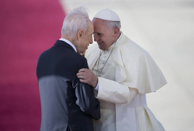 Pope Francis, right, talks with Israeli President Shimon Peres, during an official arrival ceremony at Ben Gurion airport near Tel Aviv, Israel, on Sunday, May 25, 2014. Pope Francis took a dramatic plunge Sunday into Mideast politics while on his Holy Land pilgrimage, receiving an acceptance from the Israeli and Palestinian presidents to visit him at the Vatican next month to discuss embattled peace efforts. The summit was an important moral victory for the pope, who is named after the peace-loving Francis of Assisi. Israeli-Palestinian peace talks broke down in late April, and there have been no public high-level meetings for a year.