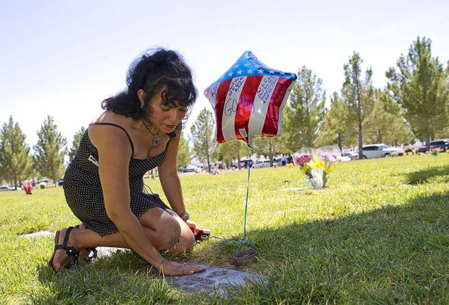Victoria D. Garcia touches the grave marker for her father following a Memorial Day ceremony at the Southern Nevada Veterans Memorial Cemetery in Boulder City Monday, May 26, 2014.