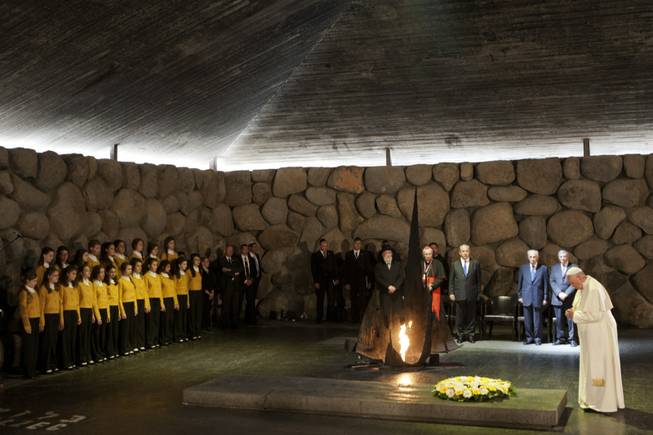 Pope Francis lays a wreath as Israel's President Shimon Peres and Israeli Prime Minister Benjamin Netanyahu stand at the Hall of Remembrance at the Yad Vashem Holocaust memorial in Jerusalem on Monday, May 26, 2014. Francis honored Jews killed in the Holocaust and in terrorist attacks, and kissed the hands of Holocaust survivors as he capped his three-day Mideast trip with poignant stops Monday at some of the holiest and most haunting sites for Jews.