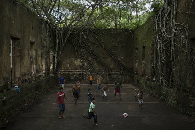 In this May 21, 2014, photo, children and adults play soccer in the ruins of Paricatuba, near Manaus, Brazil. Manaus is one of the host cities for the 2014 World Cup in Brazil.