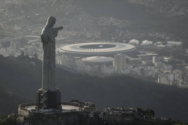 In this May 13, 2014, photo, this aerial view shot through an airplane window shows the Maracana stadium behind the Christ the Redeemer statue in Rio de Janeiro, Brazil. As opening day for the World Cup approaches, people continue to stage protests, some about the billions of dollars spent on the World Cup at a time of social hardship, but soccer is still a unifying force. The international soccer tournament will be the first in the South American nation since 1950.