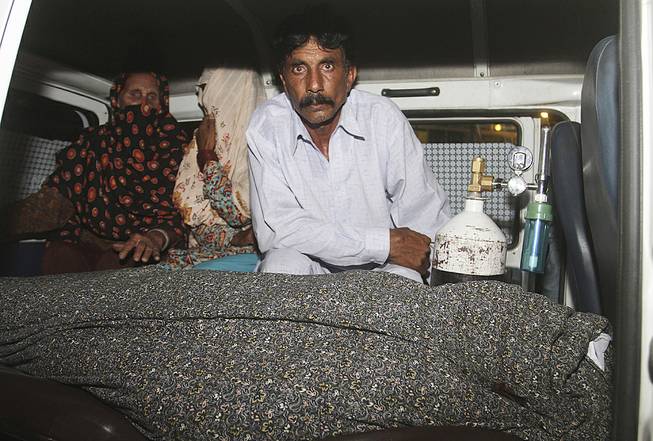 Mohammad Iqbal, right, husband of Farzana Parveen, 25, sits in an ambulance next to the body of his pregnant wife who was stoned to death by her own family, in Lahore, Pakistan, Tuesday, May 27, 2014. 