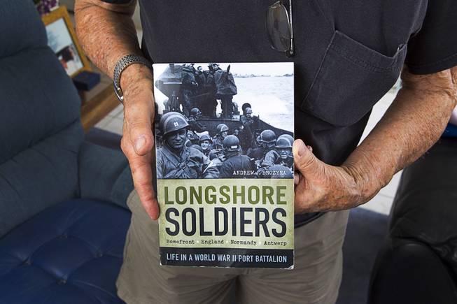 World War II veteran Gaetano "Guy" Benza holds a book written about Longshore Soldiers at his home in North Las Vegas Wednesday, May 28, 2014. Benza served as a Longshoreman, Port Battalion 297th Port Company and saw action in the invasion of Normandy. Benza and Davis Leonard, another local World War II veteran, will receive the French Legion d'Honneur award on Friday. The award is the highest honor France bestows on its citizens and foreign nationals.