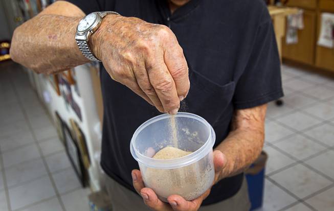 World War II veteran Gaetano "Guy" Benza shows off sand,  collected during a 2009 visit to Omaha Beach, at his home in North Las Vegas Wednesday, May 28, 2014. Benza and Davis Leonard, another local World War II veteran, will receive the French Legion d'Honneur award on Friday. The award is the highest honor France bestows on its citizens and foreign nationals.