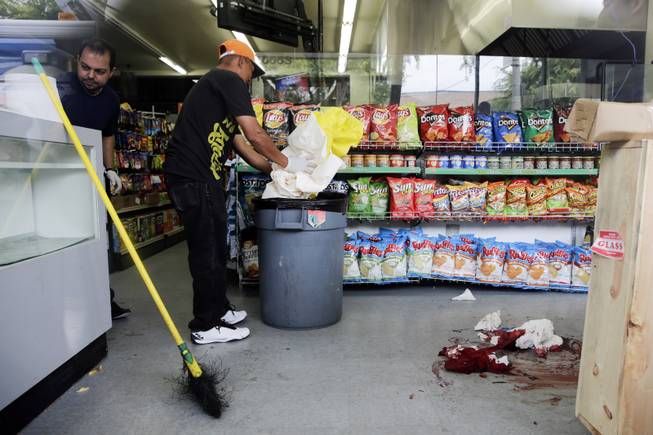 IV Deli Mart owner Michael Hassan, left, and his employee clean up the store where part of Friday night's mass shooting took place by a drive-by shooter, on Saturday, May 24, 2014, in Isla Vista, Calif. 
