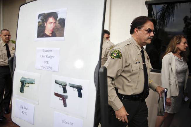 Santa Barbara County Sheriff Bill Brown, right, walks past a board showing the photos of suspected gunman Elliot Rodger and the weapons he used in Friday night's mass shooting that took place in Isla Vista, Calif., after a news conference on Saturday, May 24, 2014, in Santa Barbara, Calif. 