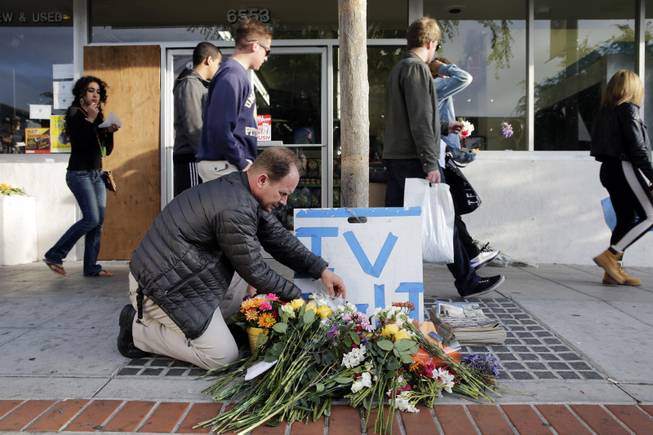 Stephen Nichols arranges flowers left in front of IV Deli Mart, where part of Friday night's mass shooting took place by a drive-by shooter, on Saturday, May 24, 2014, in Isla Vista, Calif. 