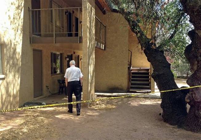 A police volunteer stands outside an apartment in Payson, Ariz., on Tuesday, May 27, 2014, after a 3-year-old boy shot and killed his 1½ -year-old brother, according to Police Chief Don Engler. According to authorities, the boys found a handgun in a neighbor's apartment and took it to another room where the shooting occurred.