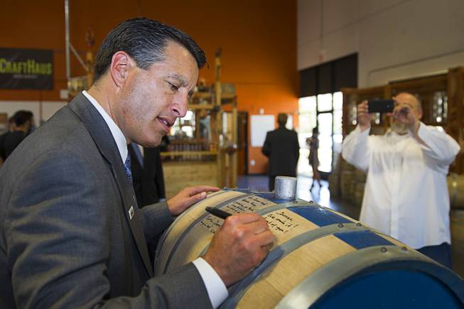 Nevada Governor Brian Sandoval signs the "Governor's Barrel" as distillery owner George Racz takes a photo at the Las Vegas Distillery in Henderson Thursday, May 29, 2014. Governor Sandoval helped fill the first bottle of "Nevada 150," a bourbon whiskey created for the Nevada sesquicentennial.