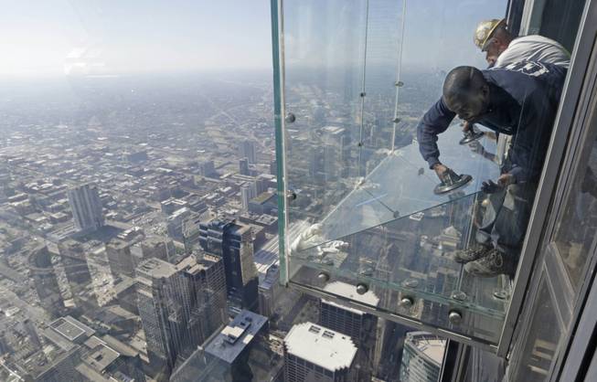 Glaziers from MTH Industries replace a layer of protective coating over the glass surface on the floor of one of four transparent ledges that jut out from the 103rd floor of the Willis Tower in Chicago on Thursday, May 29, 2014. 