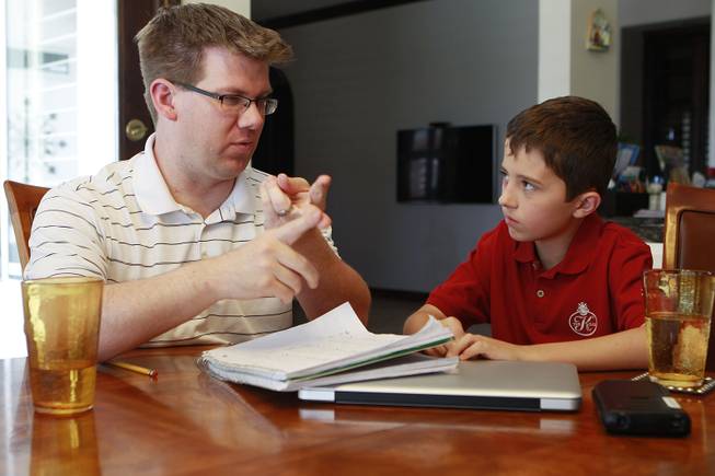 Tutor Michael Christenson explains a math problem to Aidan Swenson during a tutoring session in the Swenson's home Saturday, May 31, 2014.