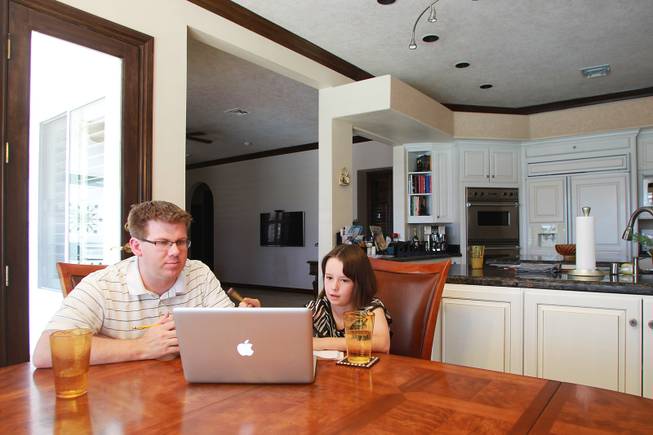 Ciara Swenson and tutor Michael Christenson use an online math program during a tutoring session in the Swenson's home Saturday, May 31, 2014.