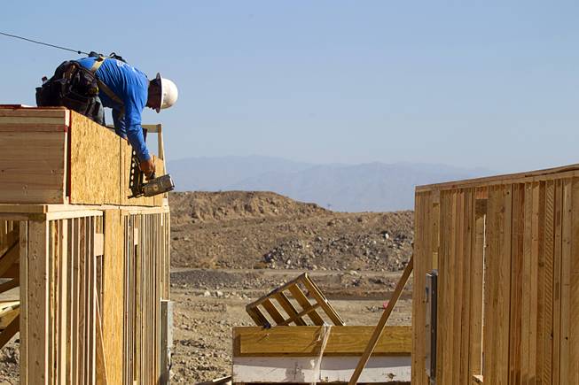 A carpenter works on a house at a KB Homes project at Inspirada in Henderson Tuesday, June 3, 2014. A number of formerly stalled or financially troubled master-planned communities are now back in business, with developers building and selling homes.