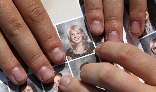 In this May 29, 2014, file photo, Wasatch High School sophomore Rachel Russell, 16, points to her altered school yearbook photo, center, in Heber City, Utah. Russell is one of several students at the school whose yearbook photos were digitally altered, with sleeves and higher necklines drawn on to cover up bare skin. 